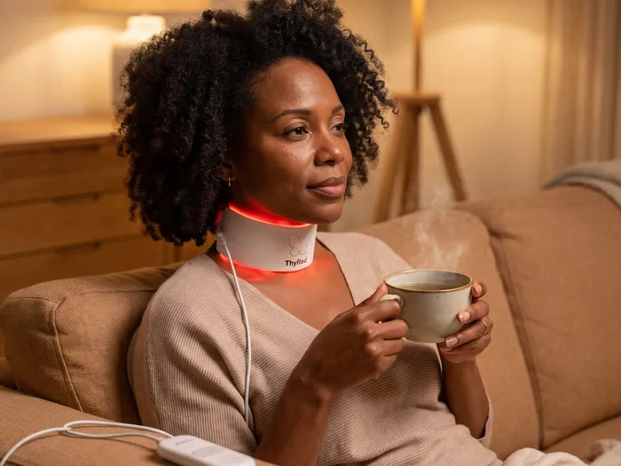 Woman on the sofa with a cup of tea, wearing ThyRed